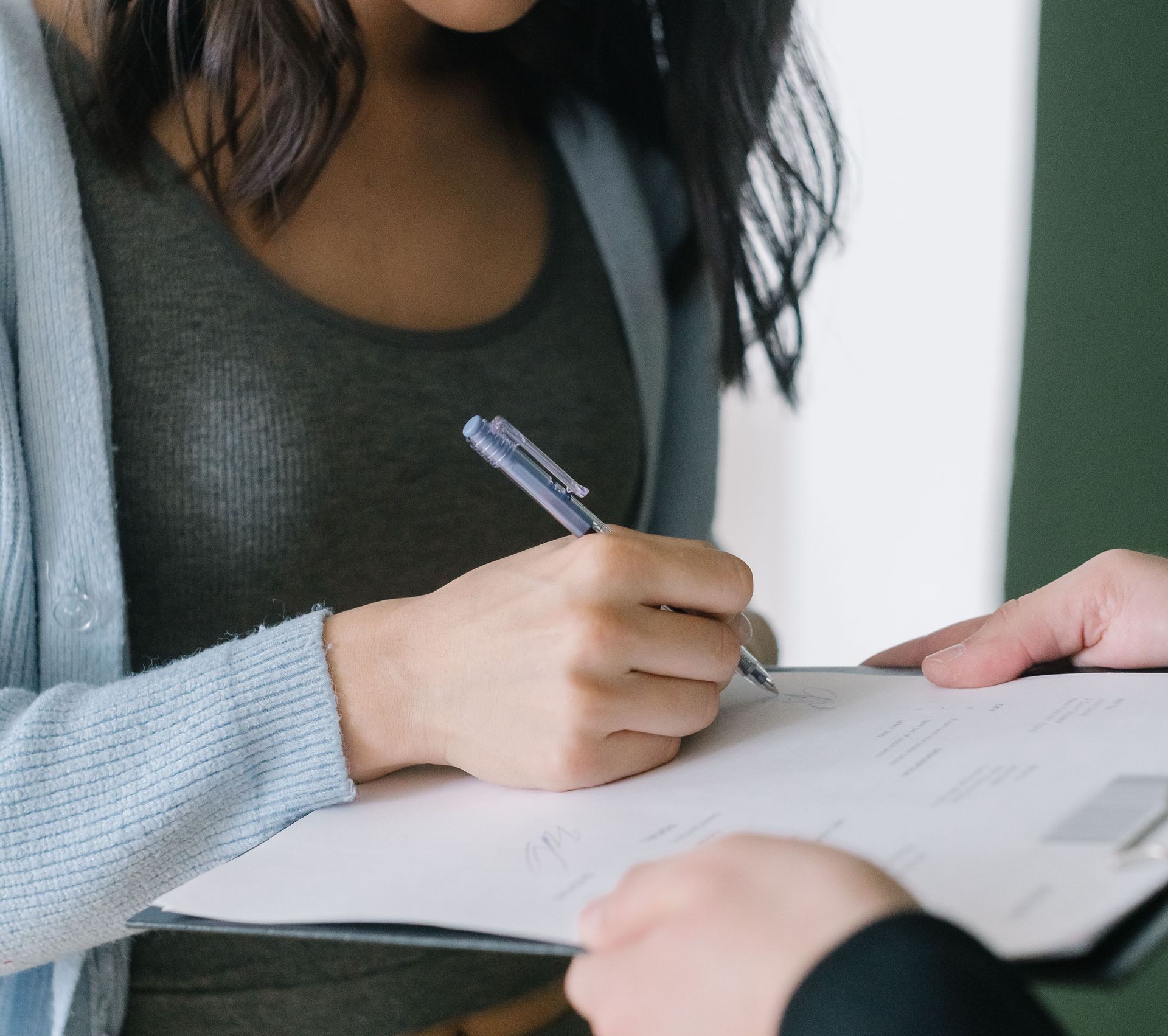 Close-up of a woman signing a document, showcasing business professionalism.